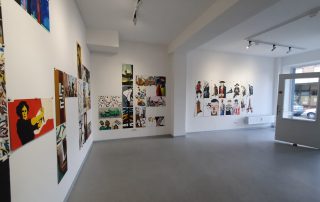 Ein weißer und heller Ausstellungsraum mit vielen kleinen Bildern den den Wänden